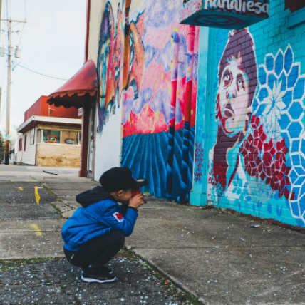 A young boy taking a photo of a colorful mural in Carlton County